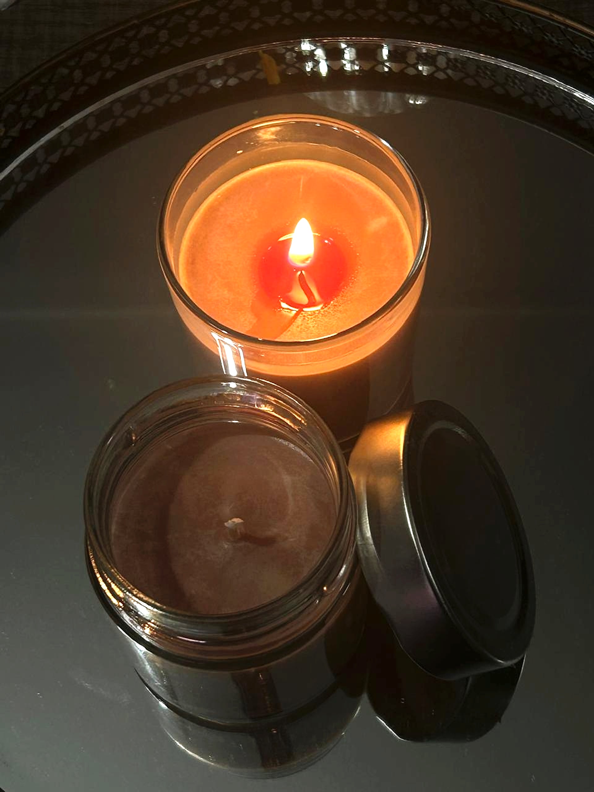 Hand-poured soy candle in a glass jar with metal lid, lit at night